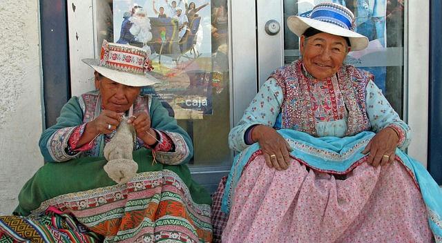 Mulheres peruanas com trajes tradicionais tecendo lã no Vale Sagrado